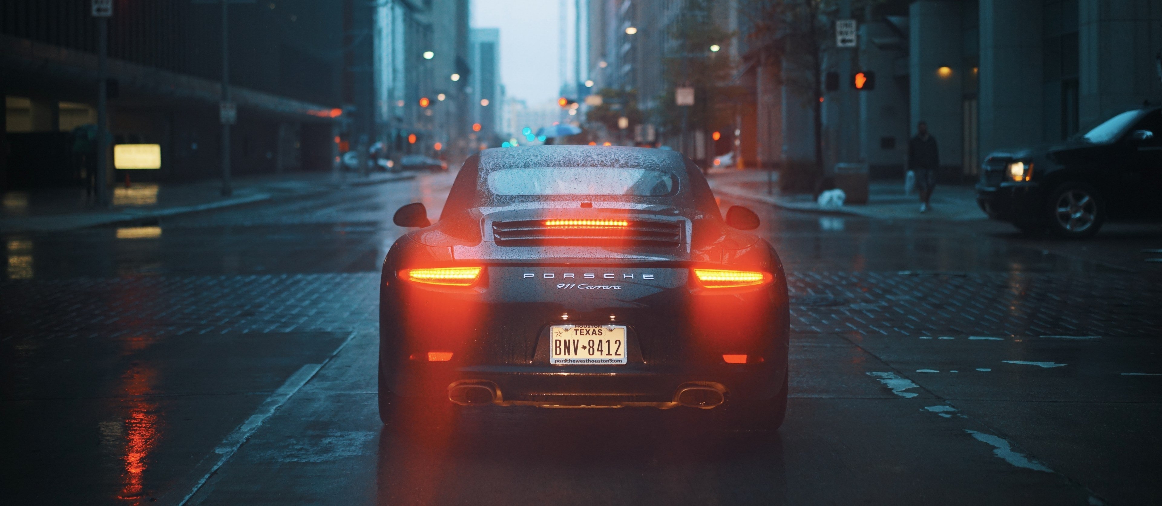 3840x1680 Wallpaper / the back of a black porsche 911 with its tail lights on on a wet street, porsche 911 on a rainy evening 4k wallpaper free download, Dual Screen