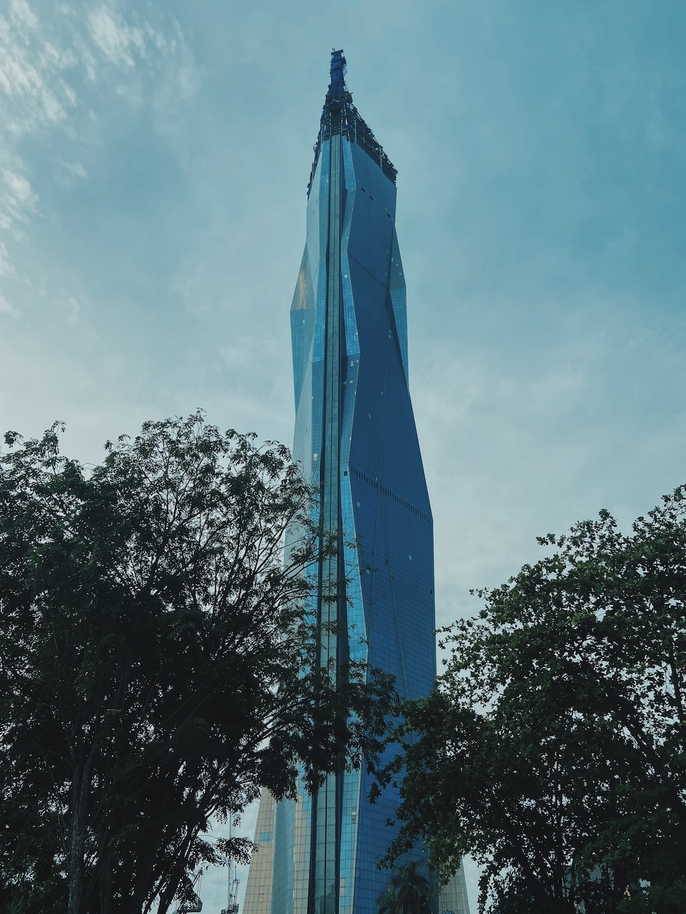 1000x1340 A very tall building towering over a forest of trees photo, Phone