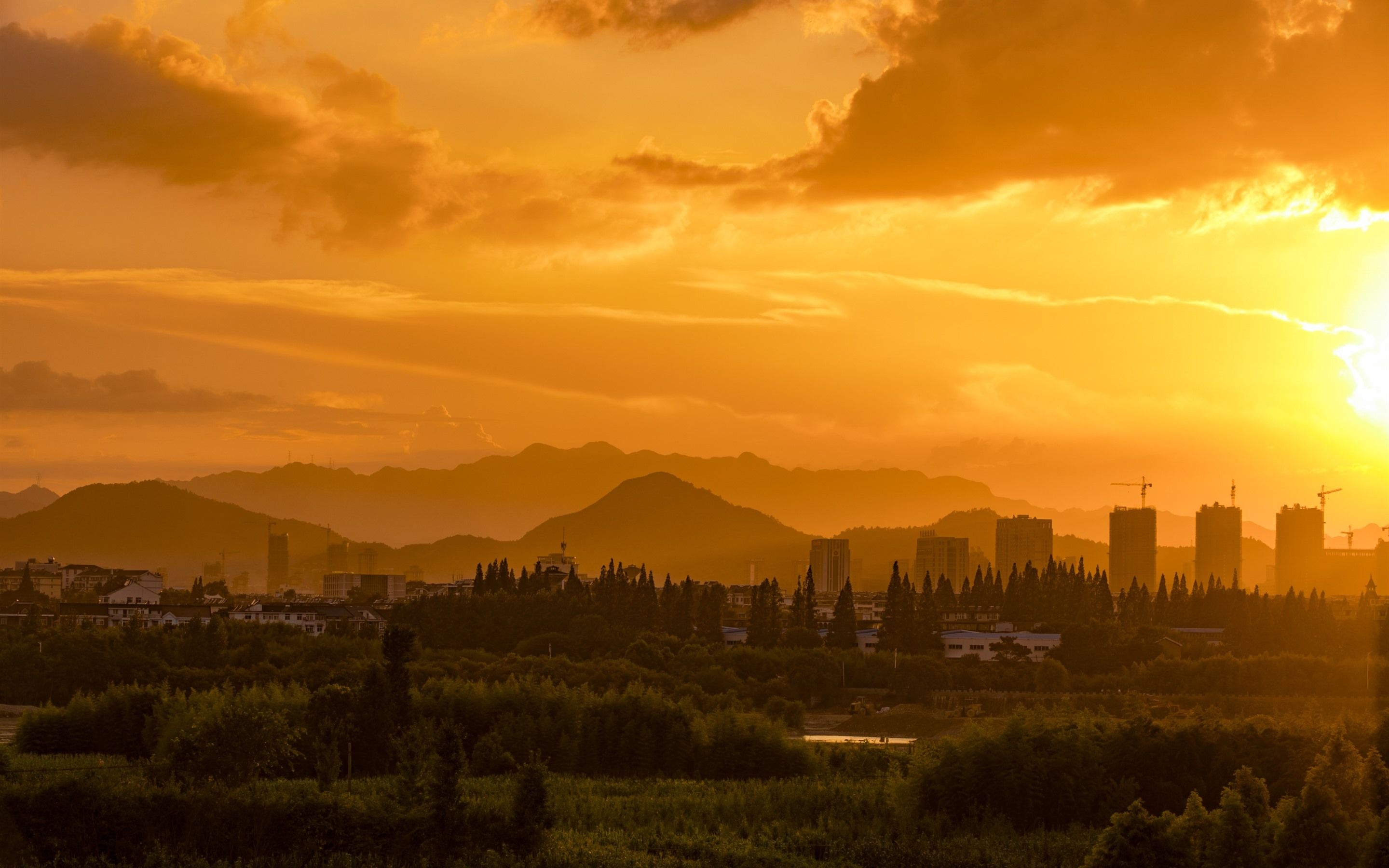 2880x1800 Wallpaper Sunset, orange sky, clouds, skyscrapers, mountains, trees  HD Picture, Image, Desktop